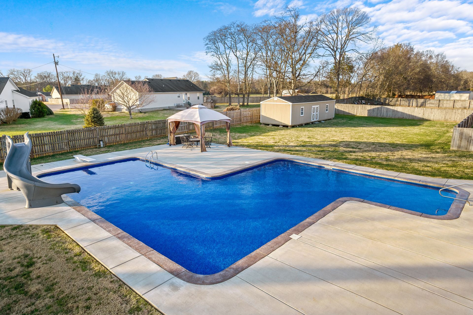 A large swimming pool with a slide in the backyard