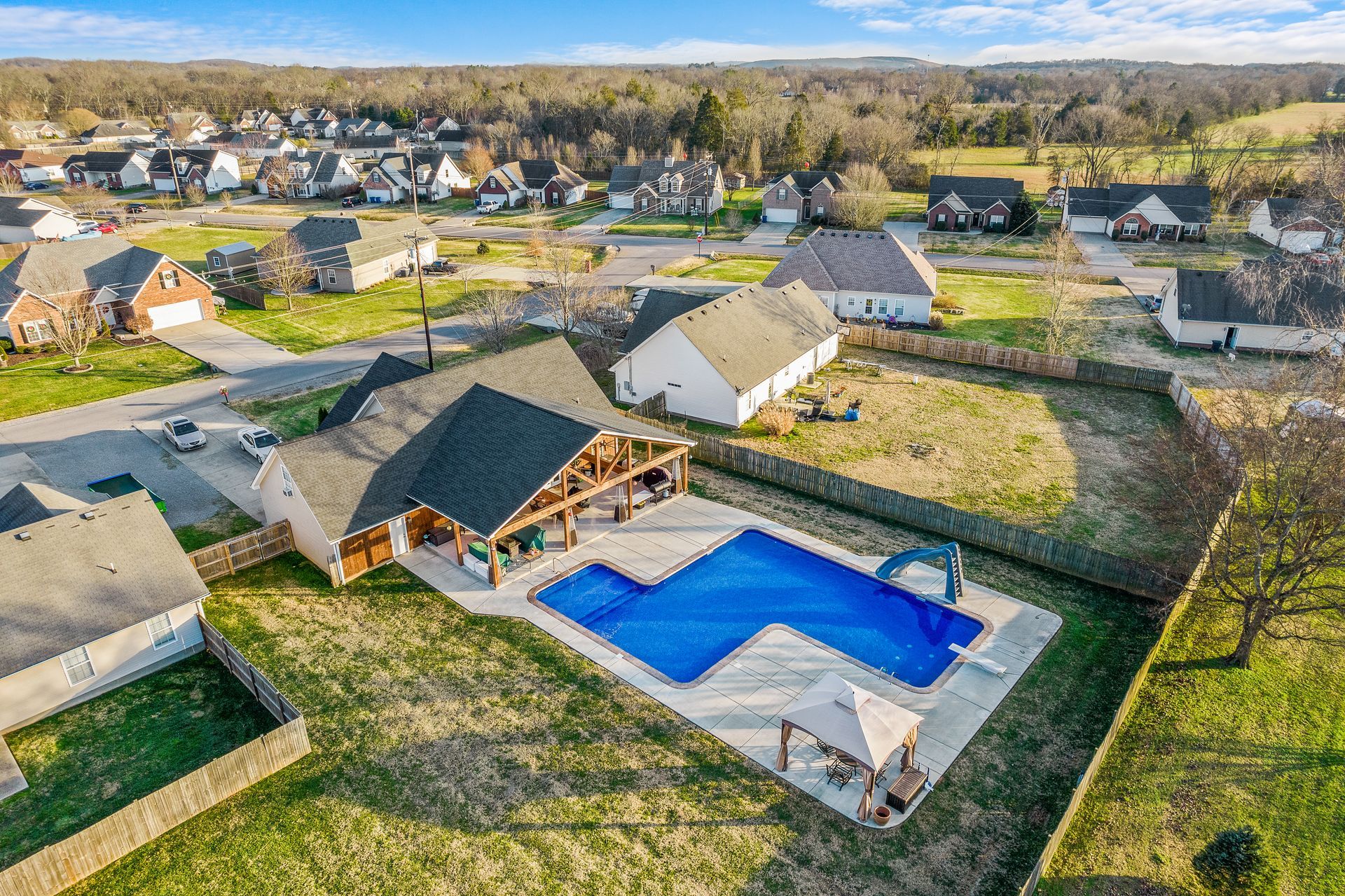 An aerial view of a house with a large swimming pool in the backyard.