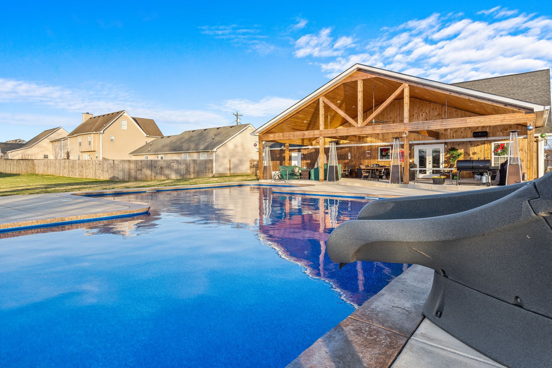 A large swimming pool with a slide and a house in the background.