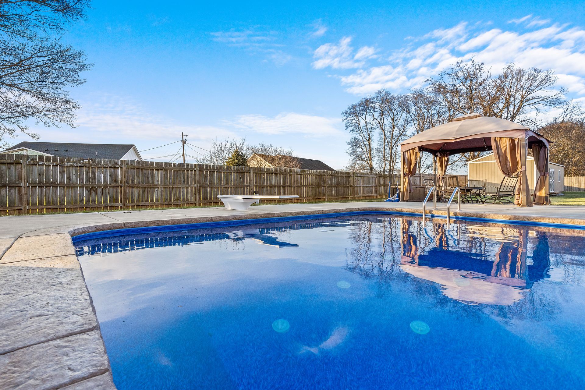 A large swimming pool with a gazebo in the backyard.