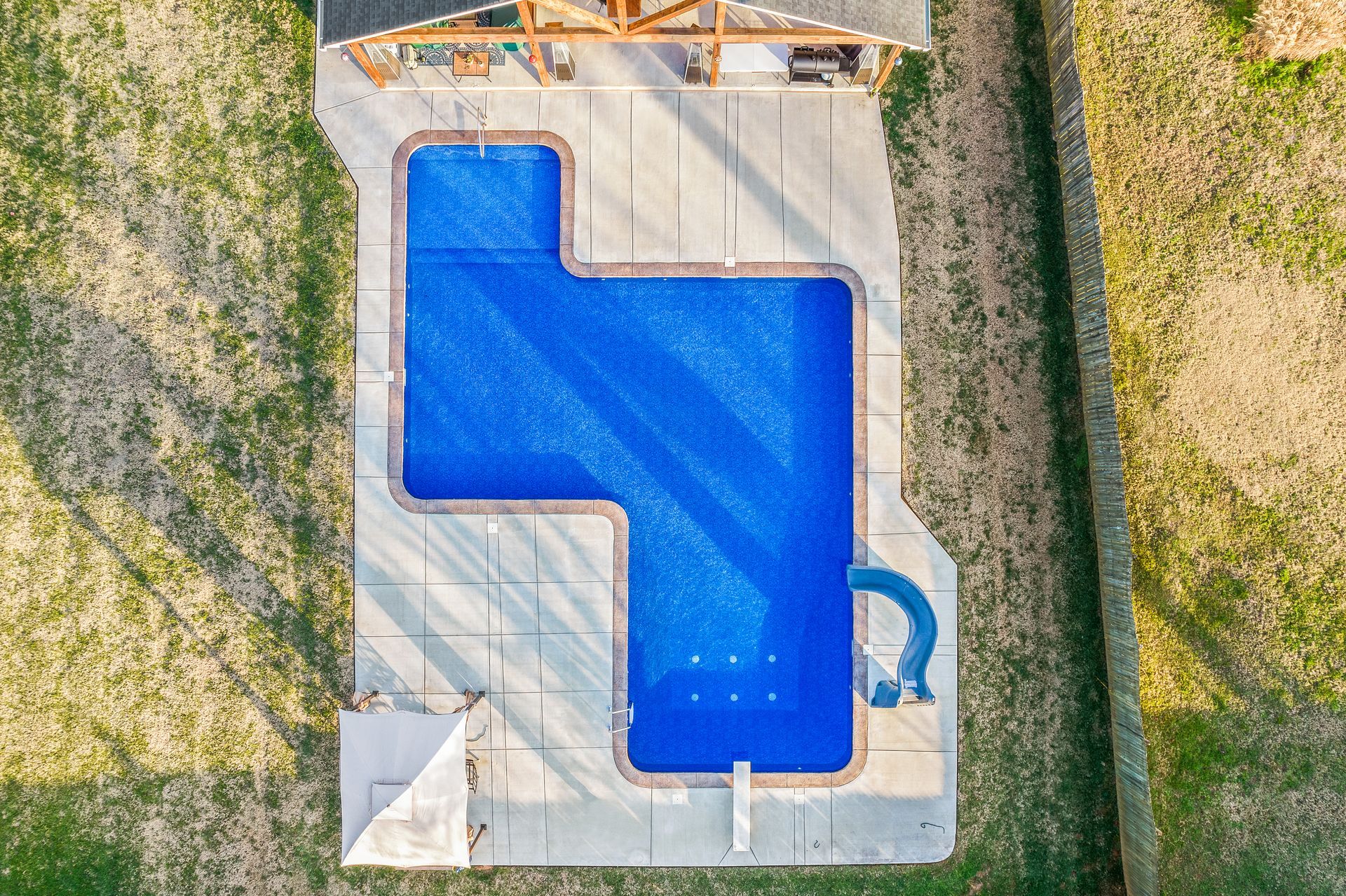 An aerial view of a large blue swimming pool surrounded by grass.