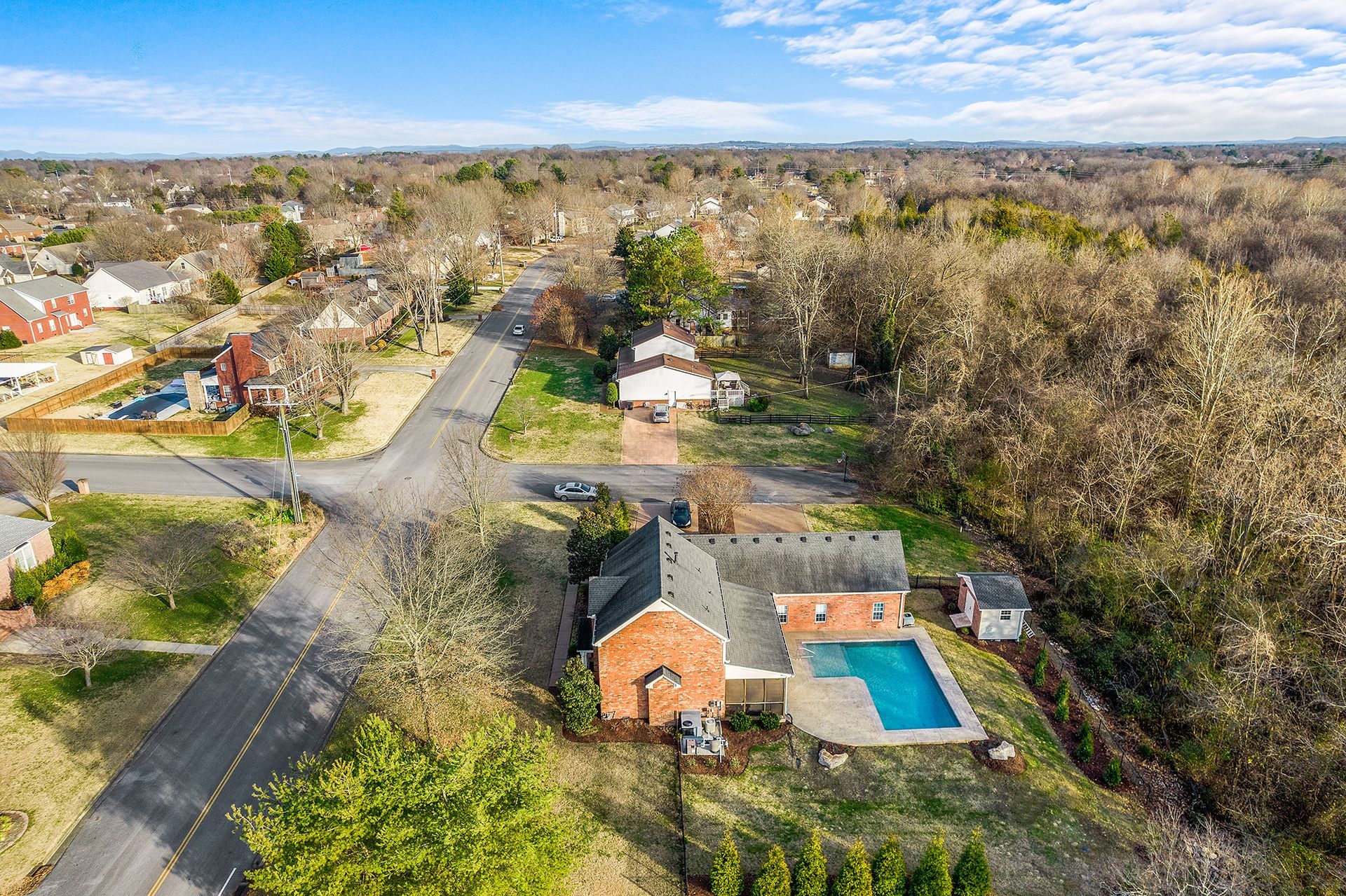 An aerial view of a house with a pool in a residential area.