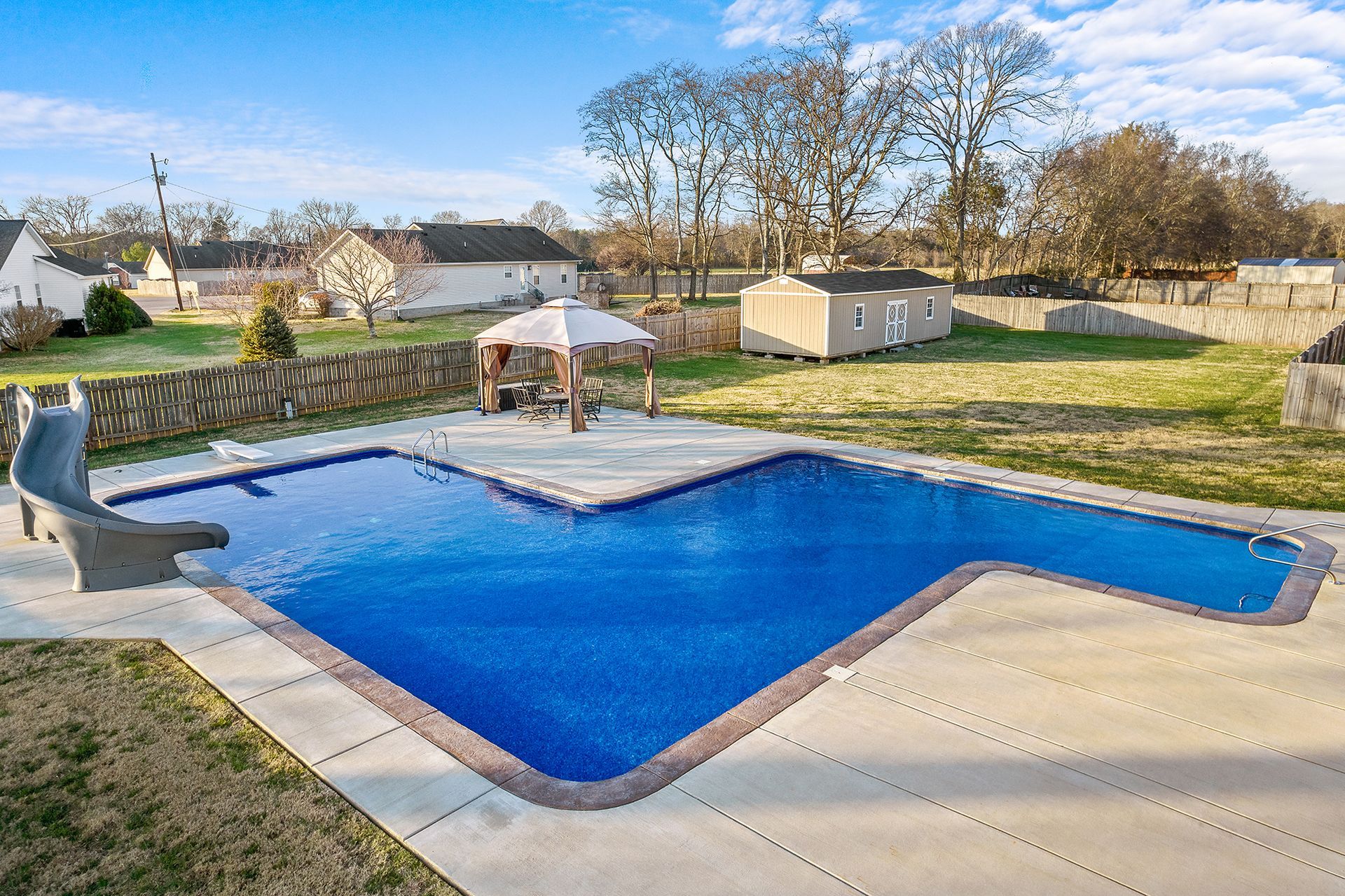 A large swimming pool with a slide in the backyard
