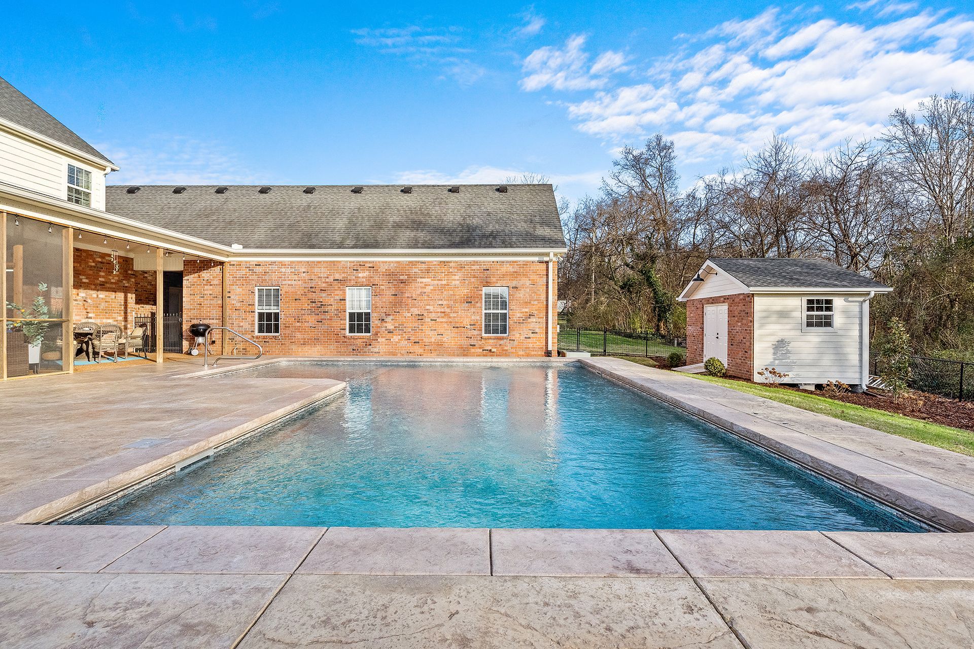 There is a large swimming pool in the backyard of a house.