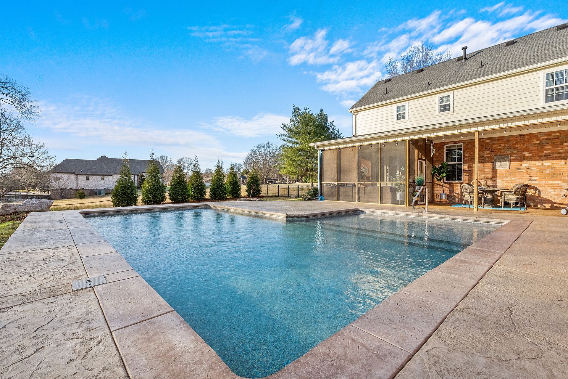 There is a large swimming pool in the backyard of a house.