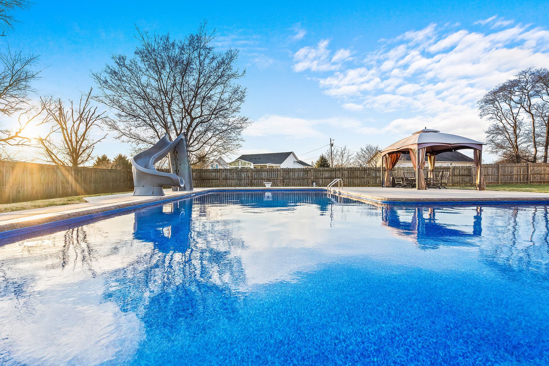 A large swimming pool with a slide and a gazebo in the backyard.