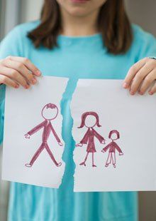 A young girl holding a broken piece of family drawing