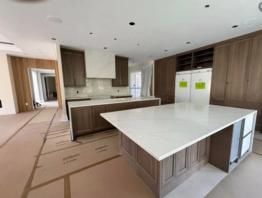 Spacious kitchen with large island and light countertops, cabinetry, and a white range hood.