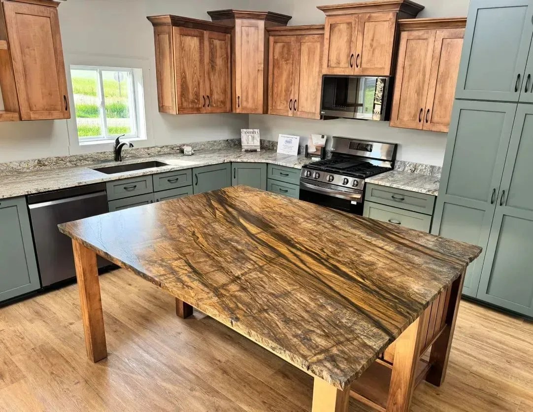 Kitchen with wooden island, teal cabinets, granite counters, wooden upper cabinets, and stainless steel appliances.