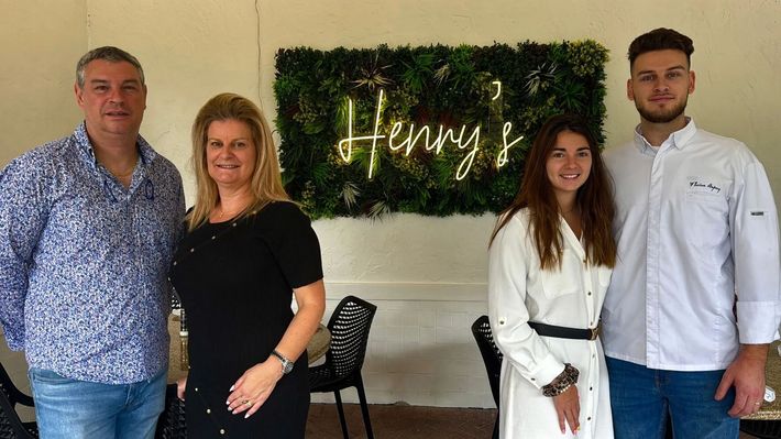 A group of people standing next to each other in front of a sign that says henry 's.
