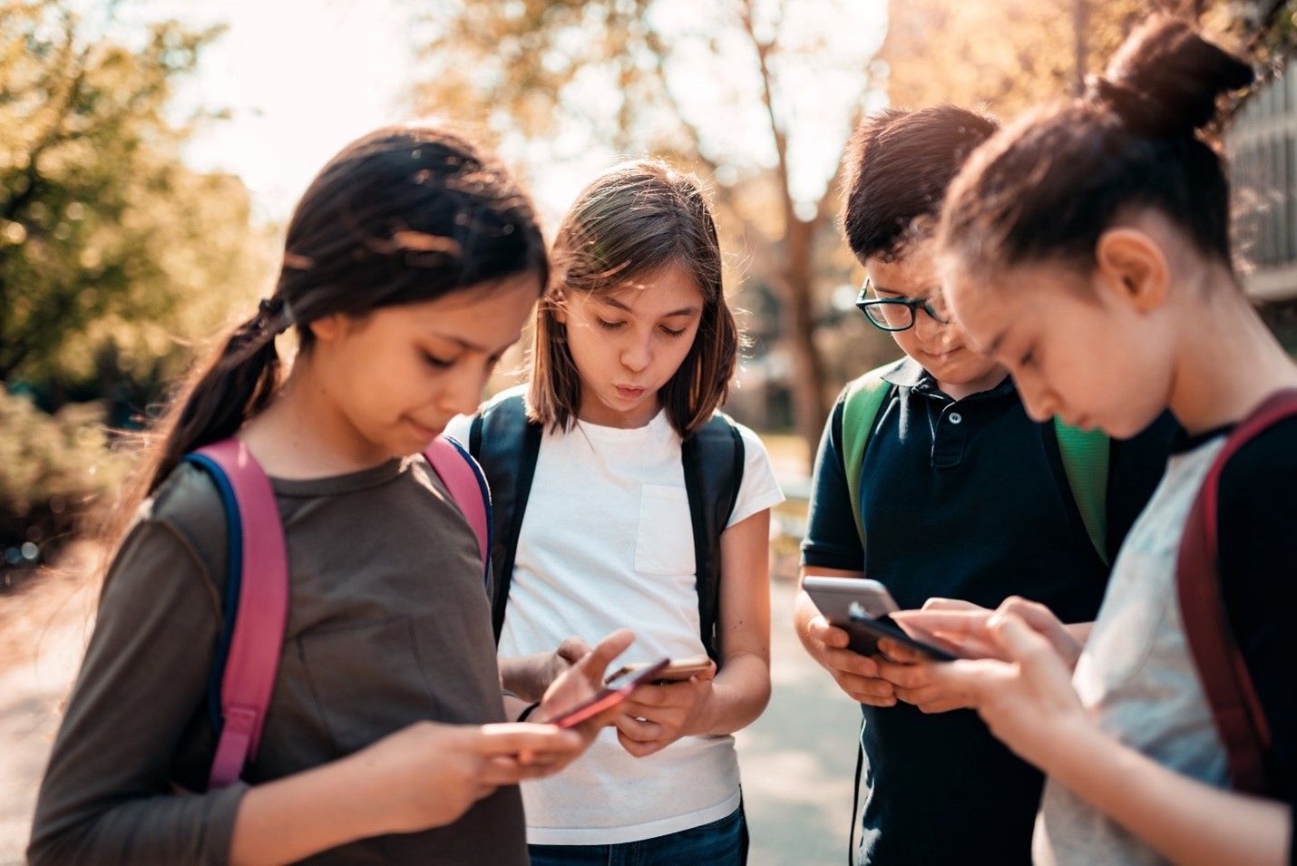 A group of children are looking at their cell phones.