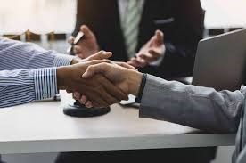 A man is shaking hands with another man while sitting at a table.
