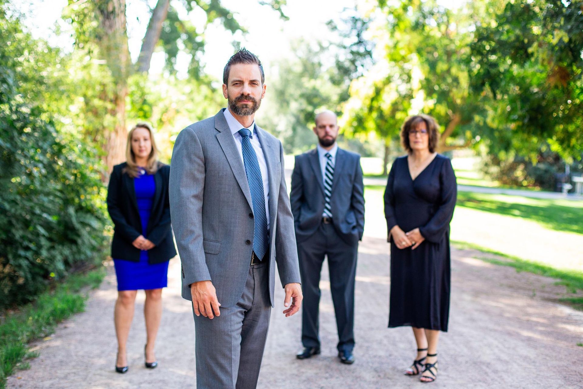 A group of people in suits and ties are standing next to each other on a dirt road.