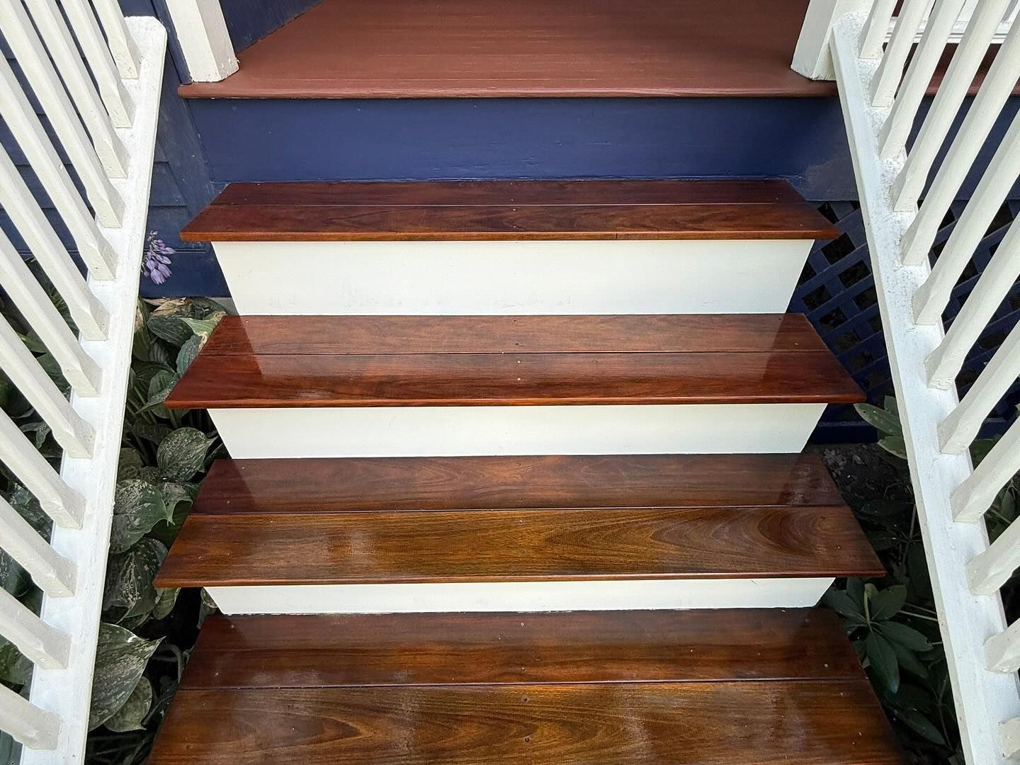 Wooden staircase with white risers, descending view, bordered by white railings.