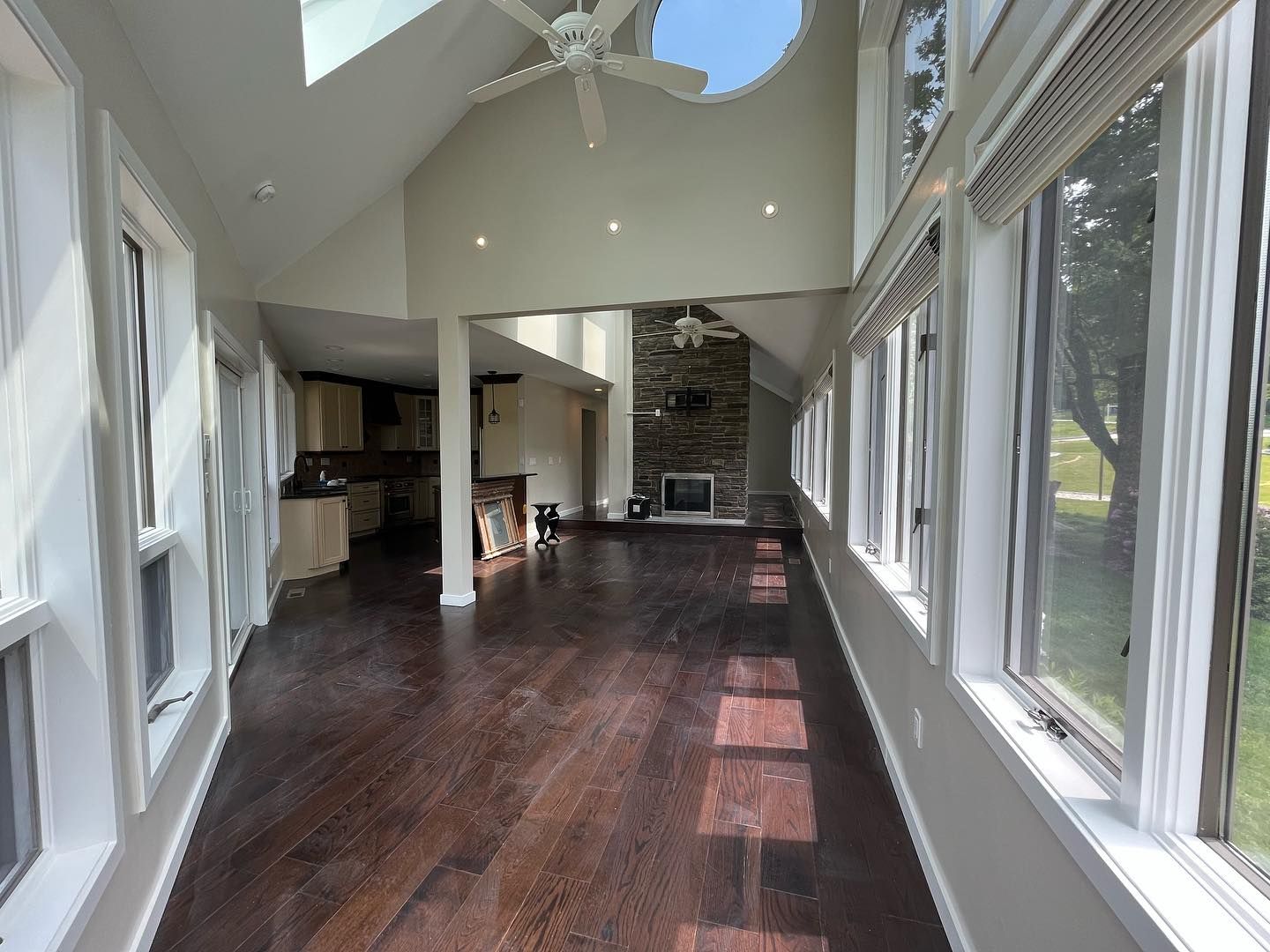 Interior view of a sunroom with hardwood floors, many windows, and a fireplace.