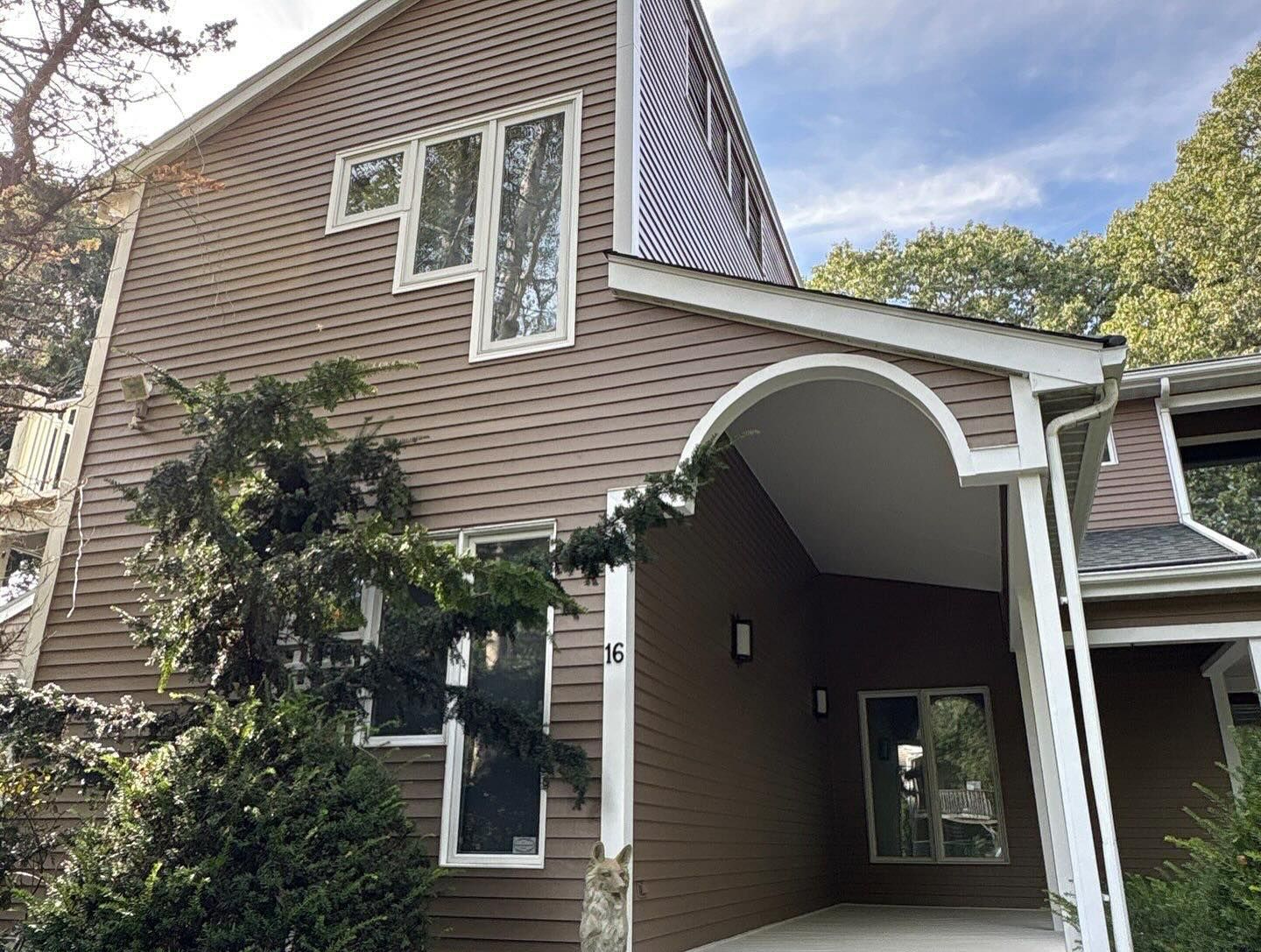 Brown two-story building with white trim, multiple windows, and a covered entrance. Overcast sky.