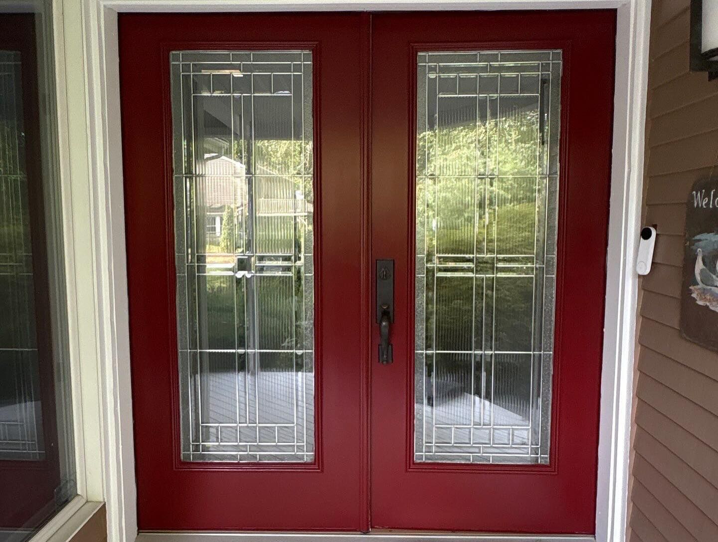 Red double doors with glass panels and a black handle.
