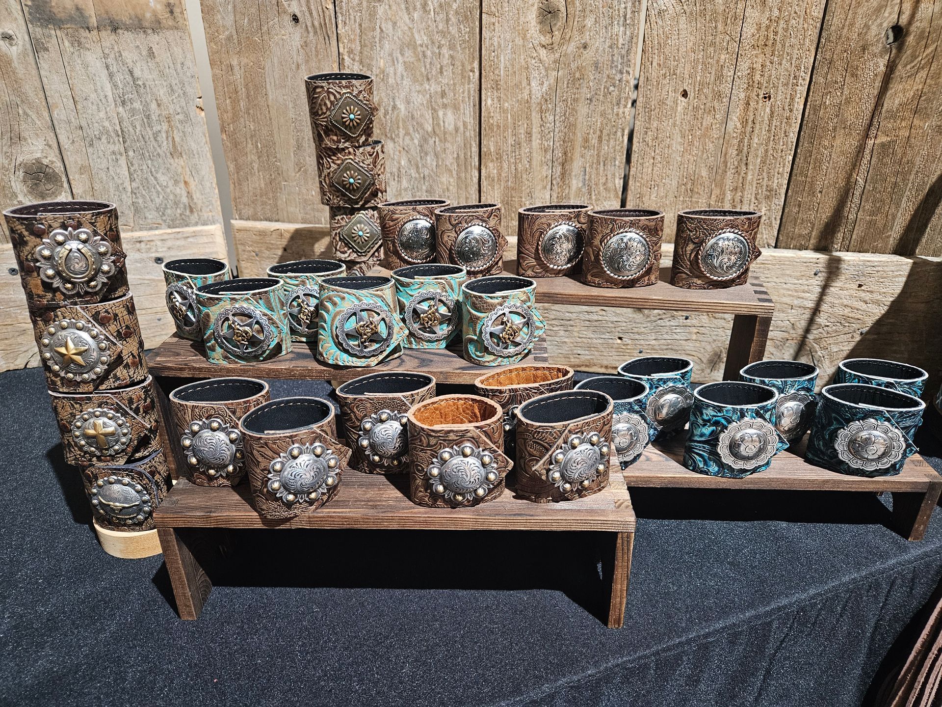 A collection of handcrafted, textured leather cuffs with silver embellishments displayed on wooden stands.