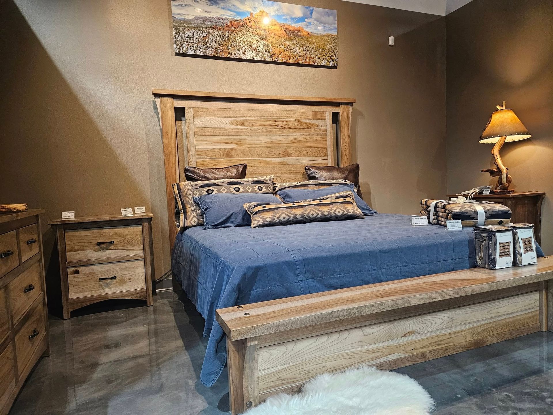 A room with a rustic recliner, a cow-print accent chair, a matching lamp with a base, and a small cow portrait on the wall.