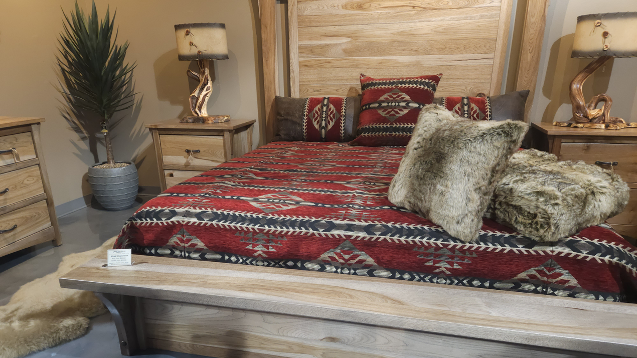 Rustic bedroom with a wooden bed, red patterned bedding, fur pillows, and matching nightstands.