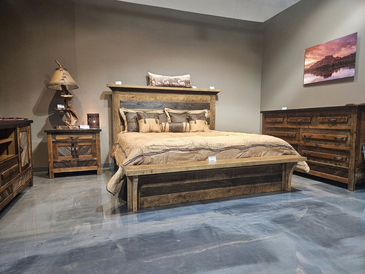 A rustic bedroom set with a wooden bed frame, matching nightstand, and dresser on a gray concrete floor.