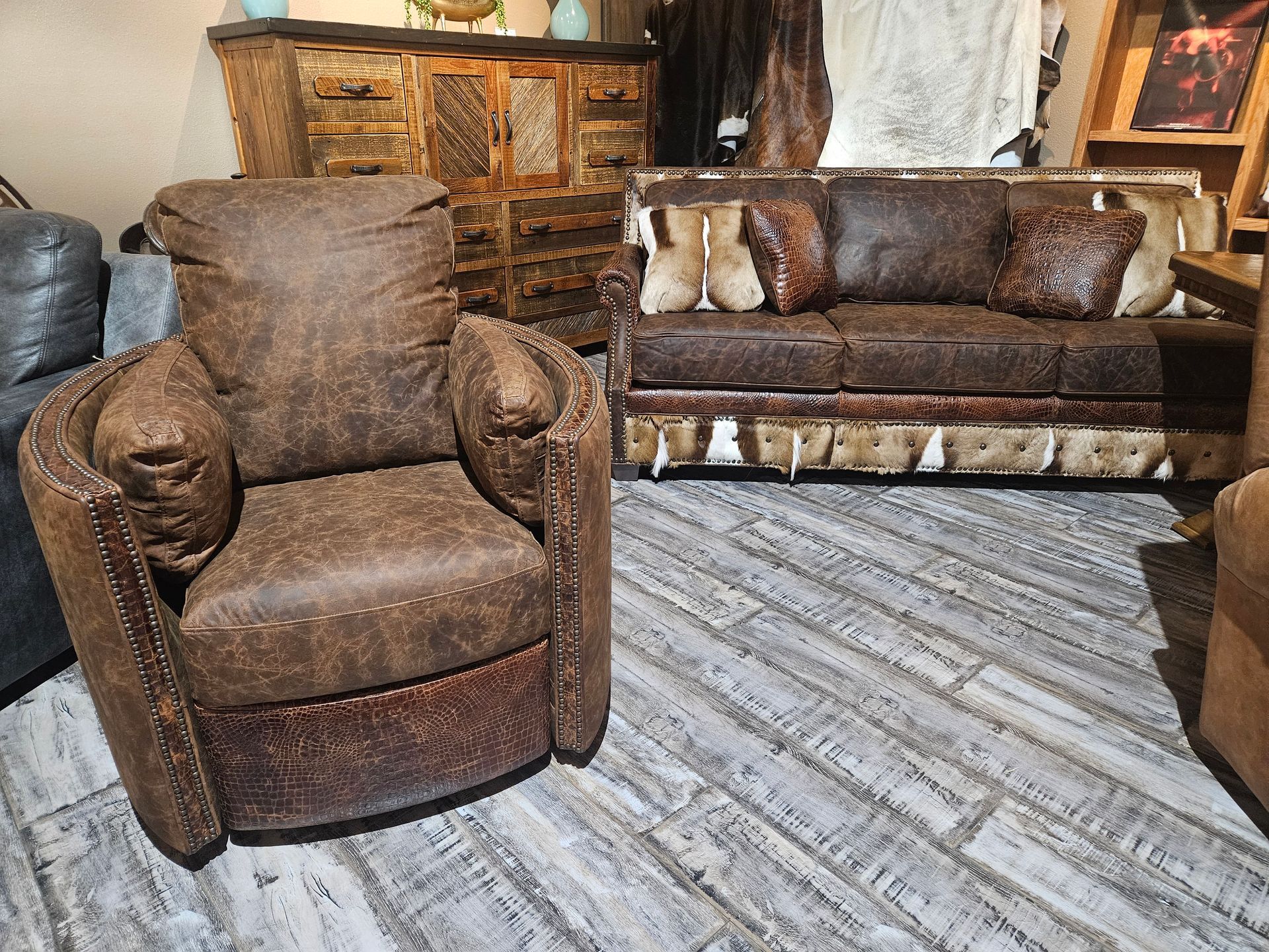 Brown leather armchair and matching sofa on a patterned rug in a rustic living room.
