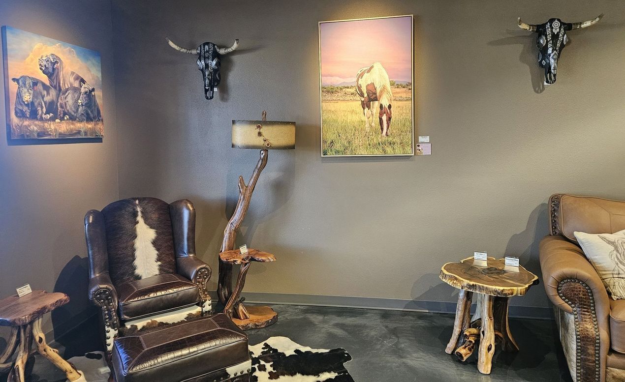 A rustic western-style living area features a leather chair with cowhide accents, wood tables, and animal skull wall decor.