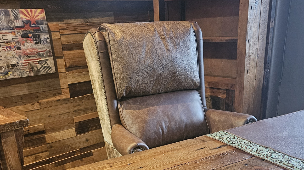 Padded gray armchair in a rustic wooden room beside a table.