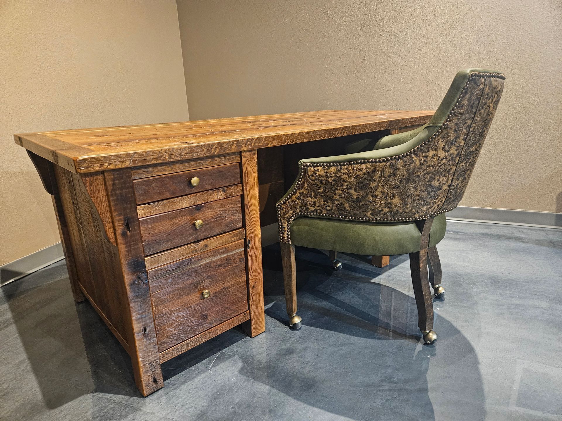Wooden desk with drawers and a patterned chair in a room.