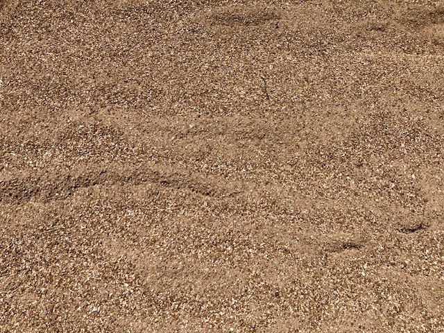 Close-up of brown sandy ground with small pebbles and subtle ripples
