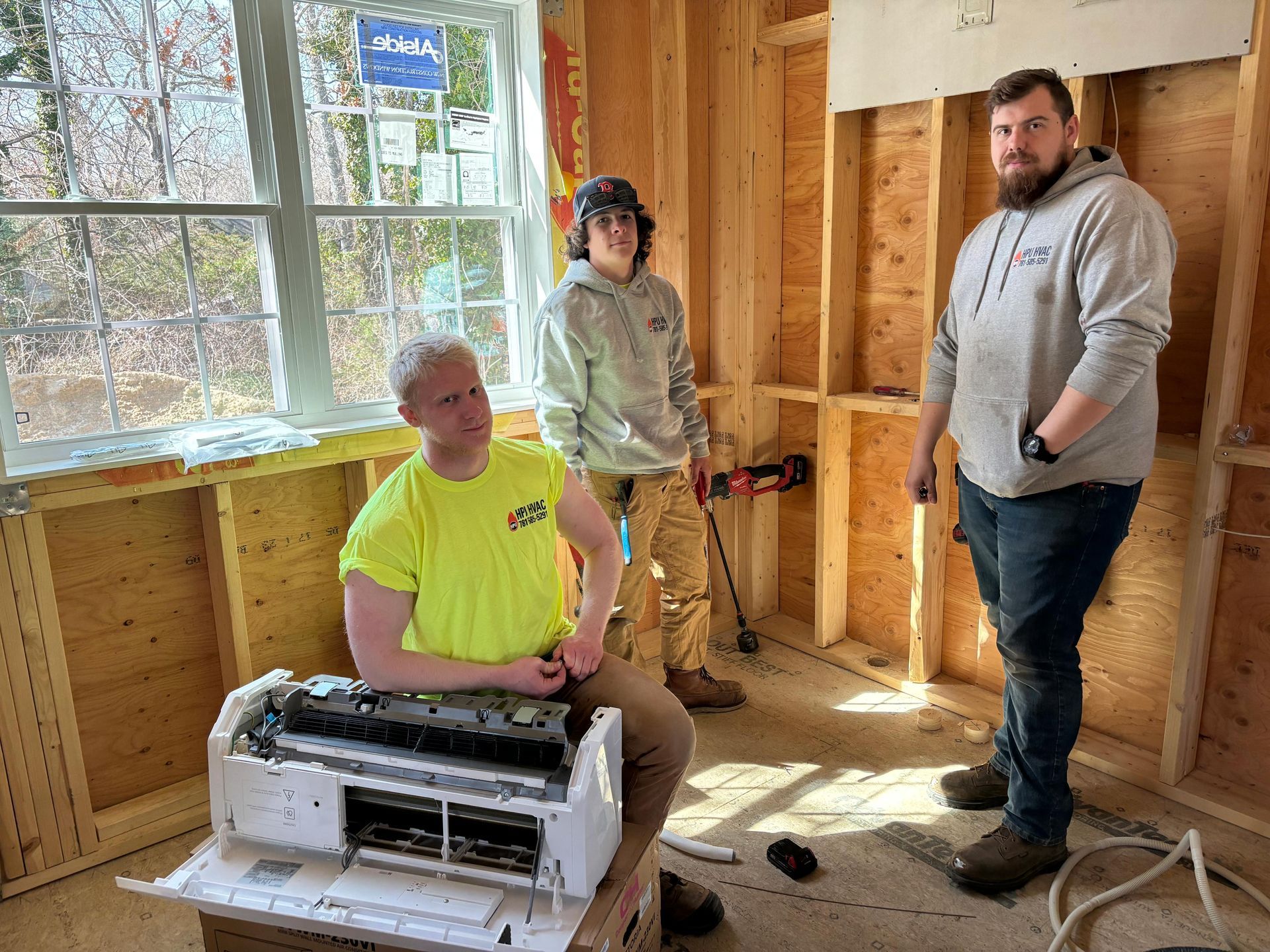 A group of men are working on an air conditioning system in an under-construction house