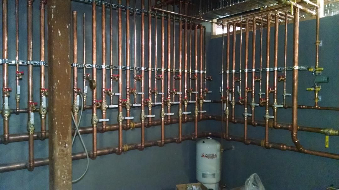 A hallway filled with pipes and a boiler in a building.