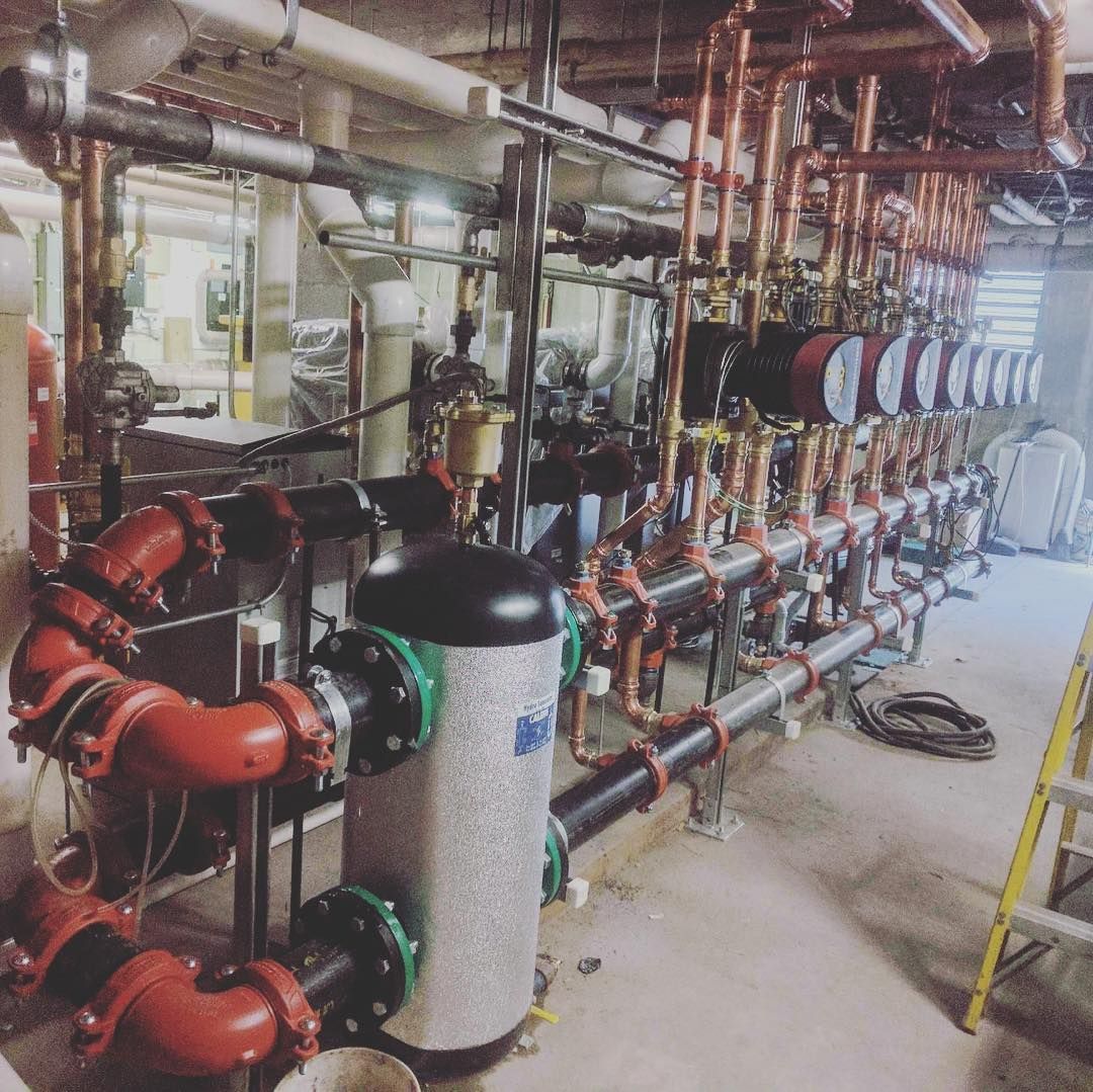A man is standing in a room with pipes hanging from the ceiling