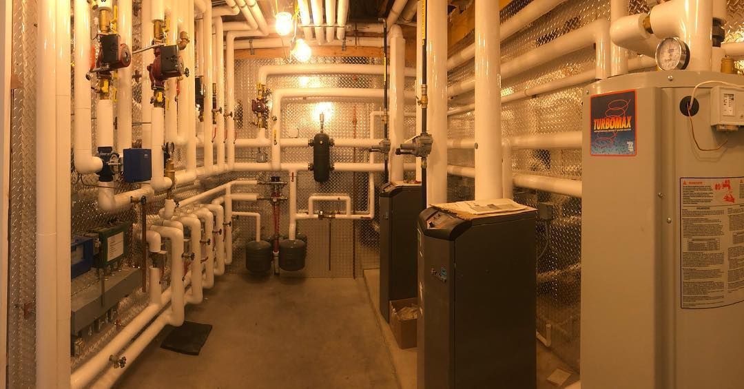 A hallway filled with pipes and a boiler in a building.