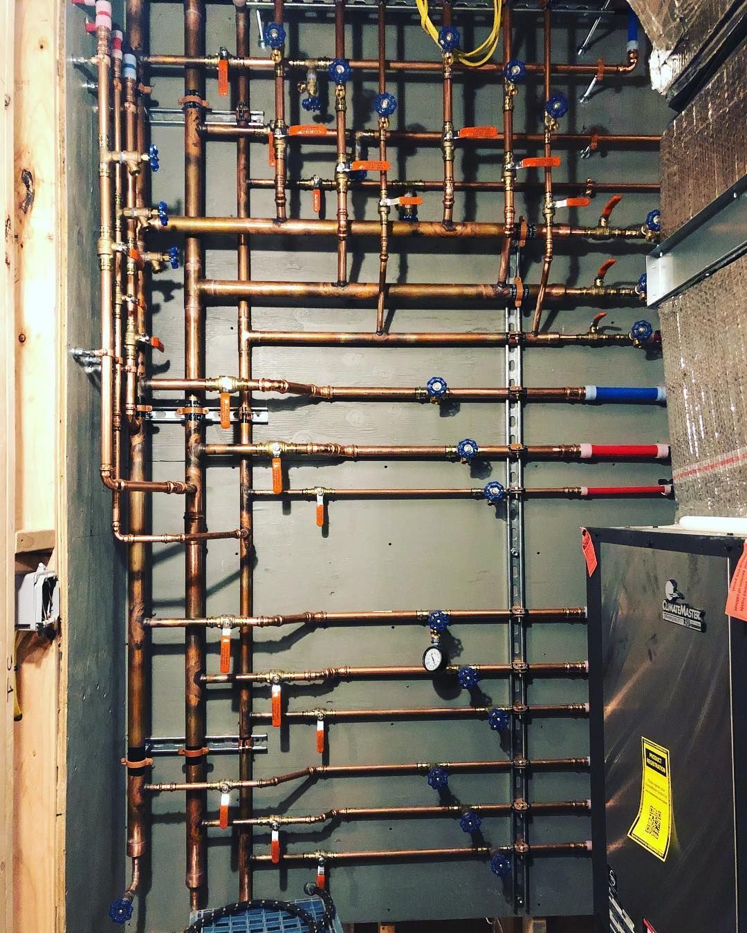 A room filled with lots of white pipes and a red tank