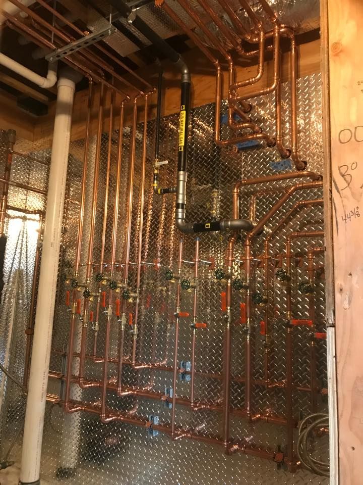A man standing on a ladder working on a water heater