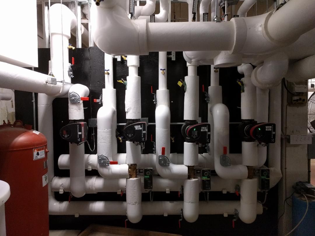 A wall of copper pipes with a yellow warning sign on it