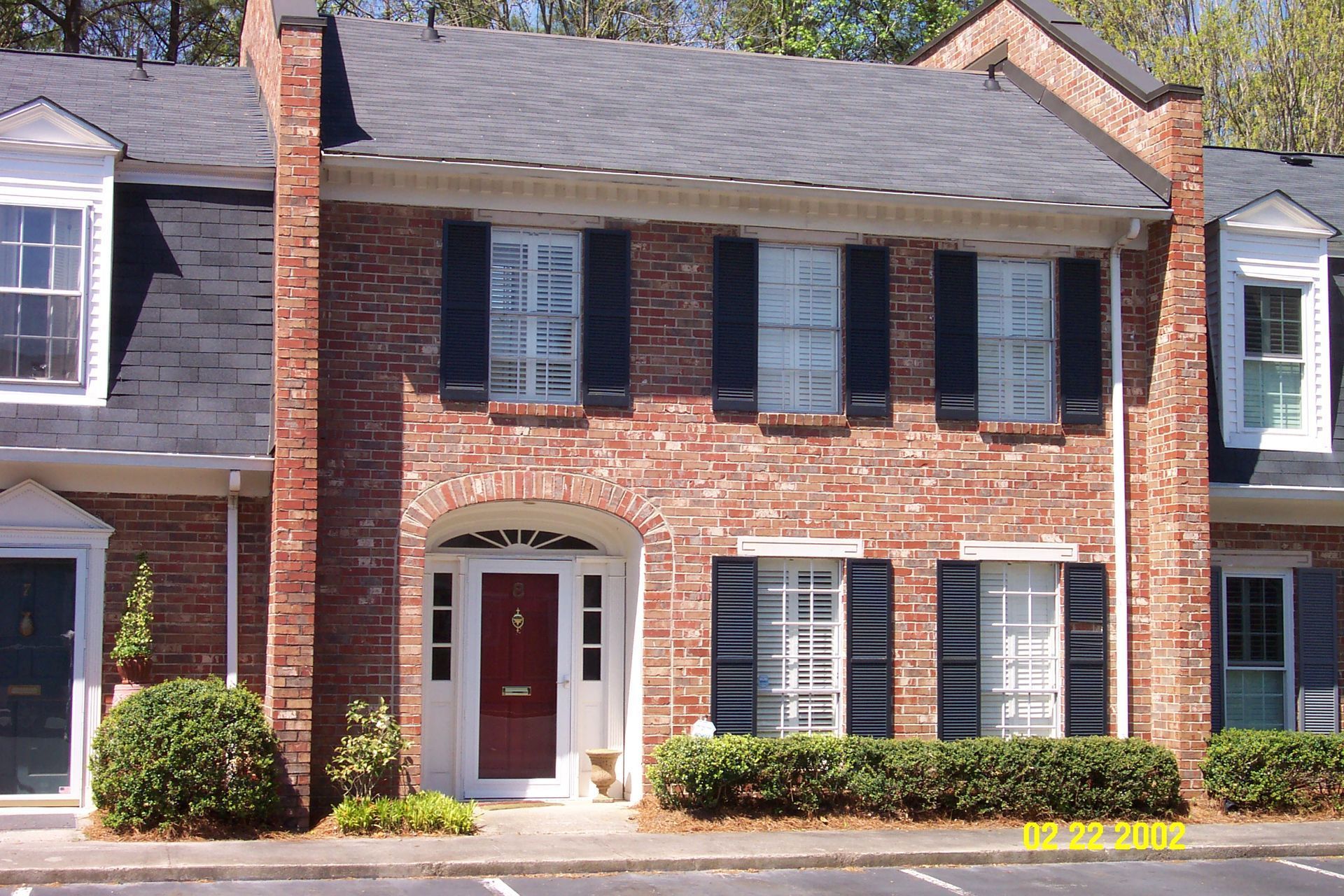 A brick house with black shutters and a red door