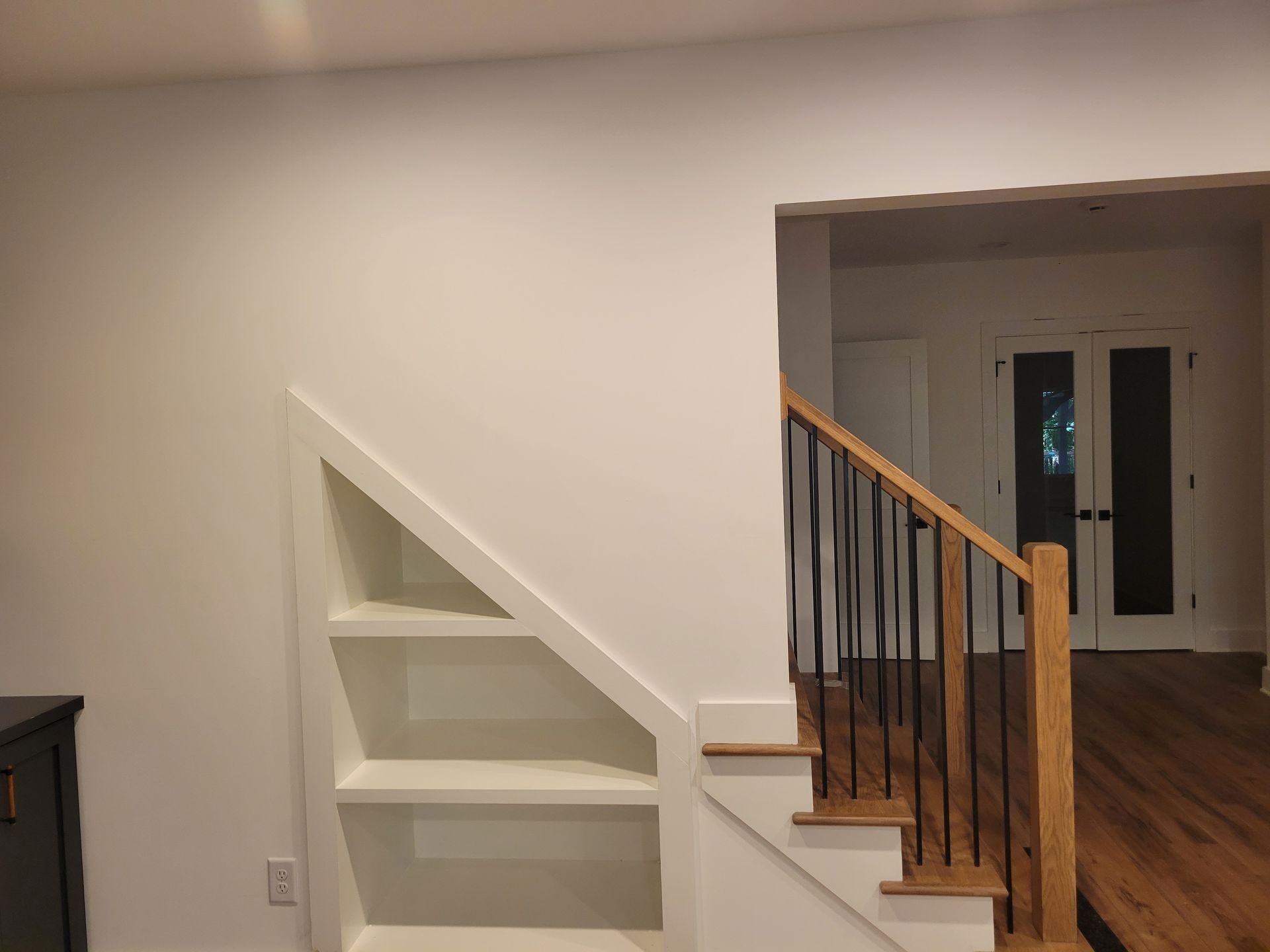 a staircase with a wooden railing and shelves underneath it in a living room .