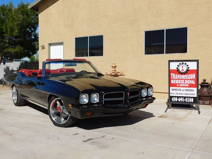 Black convertible Pontiac GTO in front of a transmission repair shop.