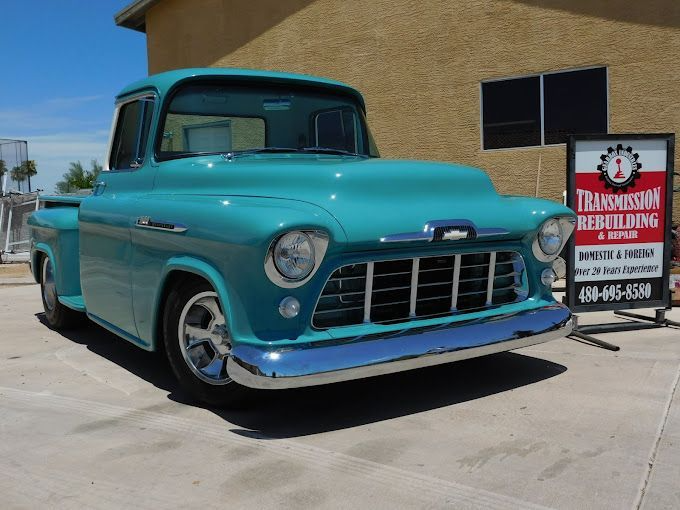 Teal vintage Chevrolet pickup truck parked in front of a business, with a sign that says 
