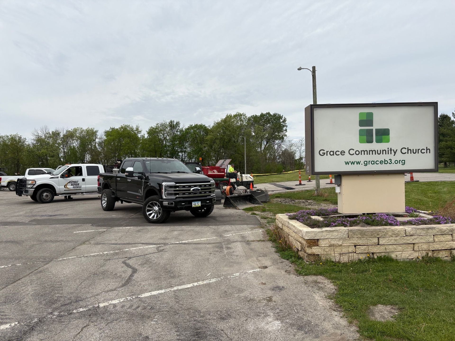 Parking lot outside Grace Community Church with several parked vehicles and a sign in front.