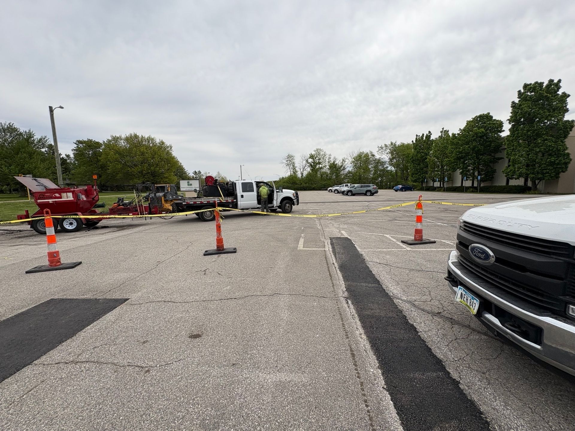 Parking lot with tow trucks, cones, and a white van blocking off a roadway section