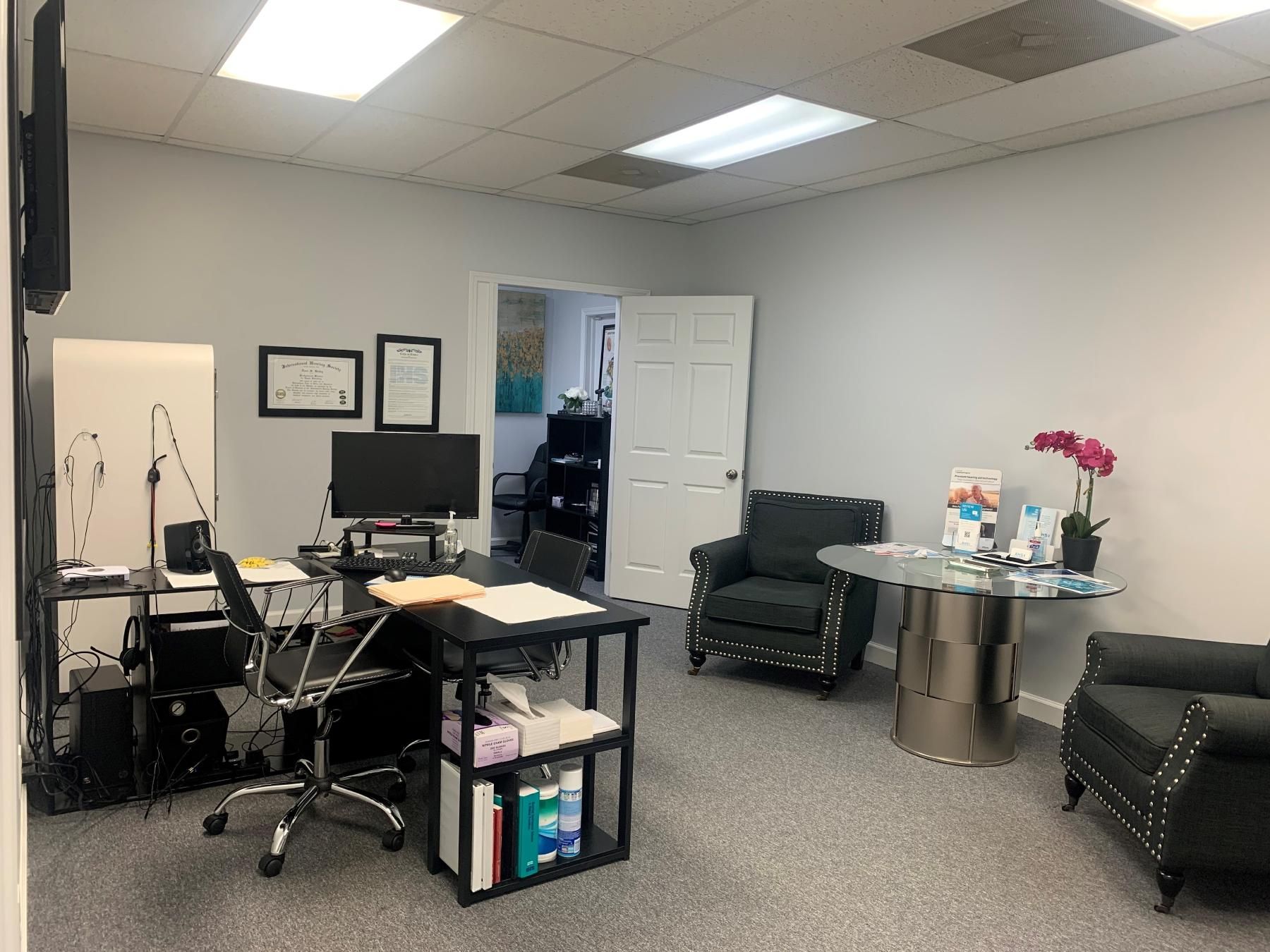 Office interior with a desk, two armchairs, and a door to another room.