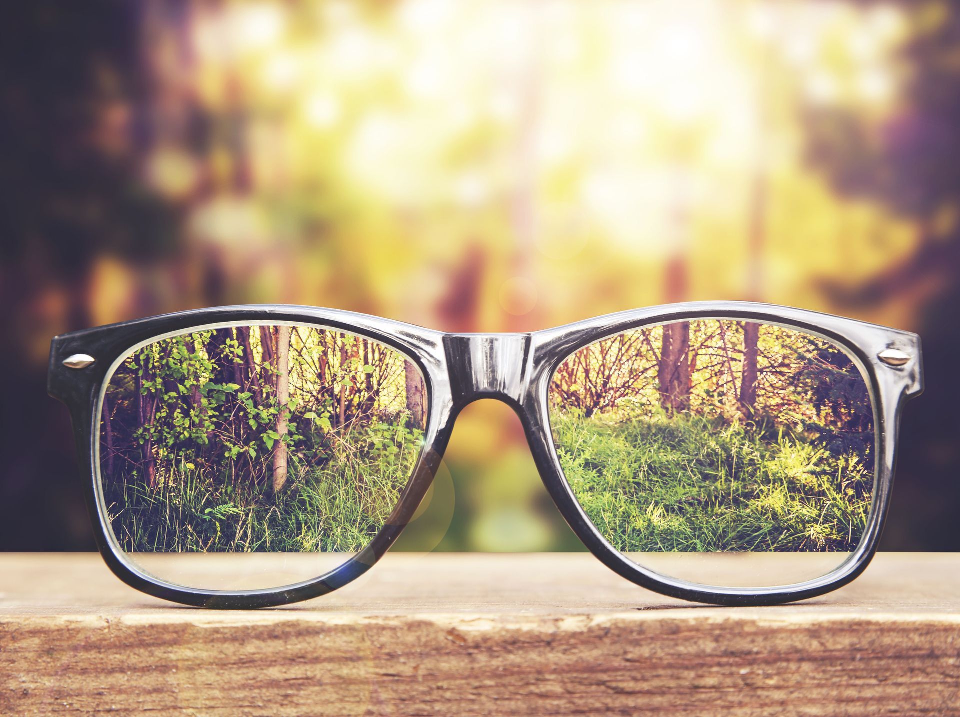 A pair of glasses sitting on top of a wooden table.
