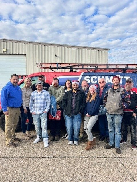 A group of people are posing for a picture in front of a schmidt van.