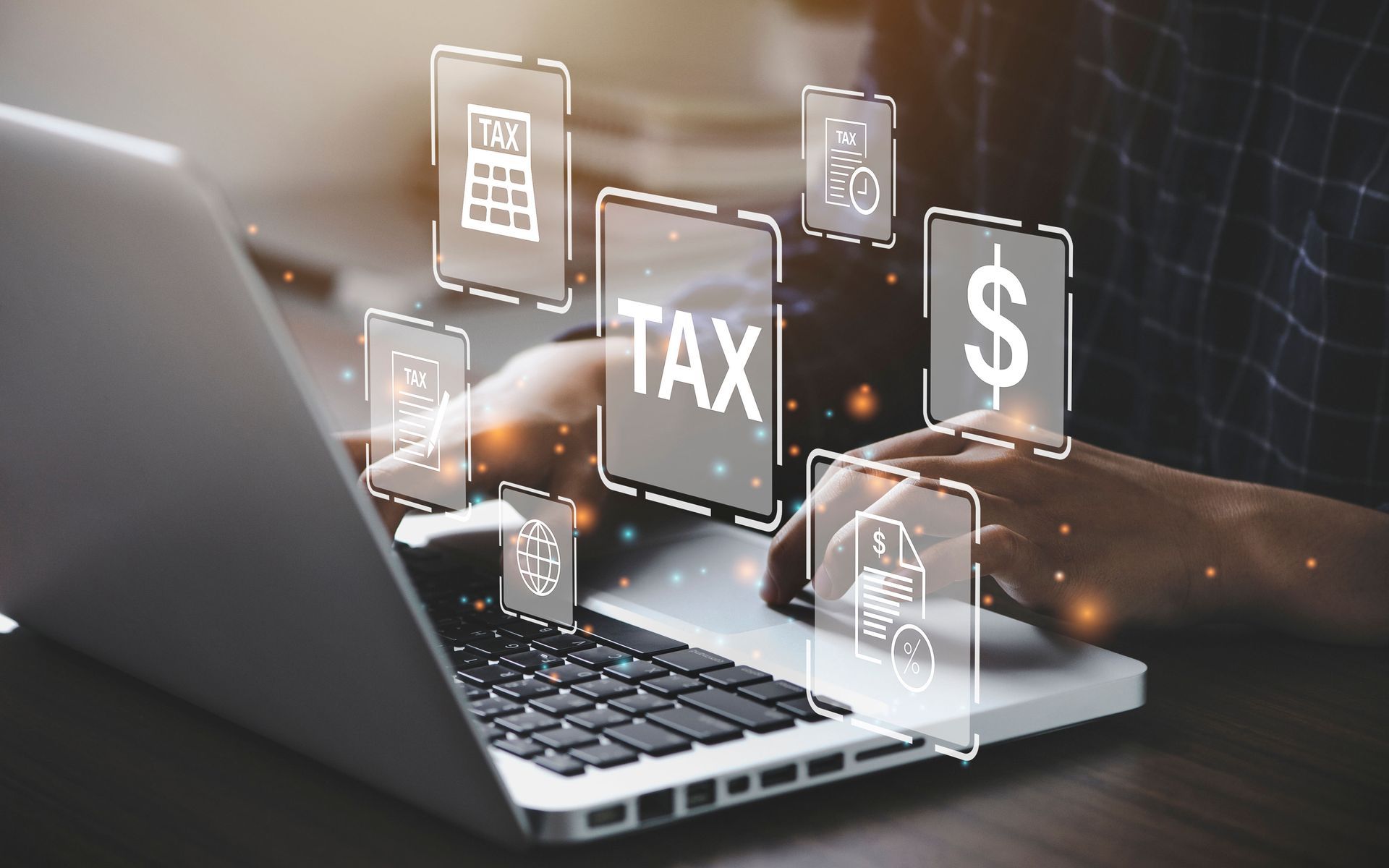 Hands typing on a laptop with floating tax and dollar icons over a digital interface.