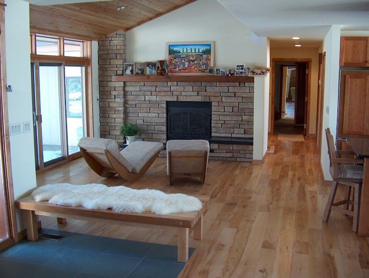 A living room with hardwood floors and a stone fireplace