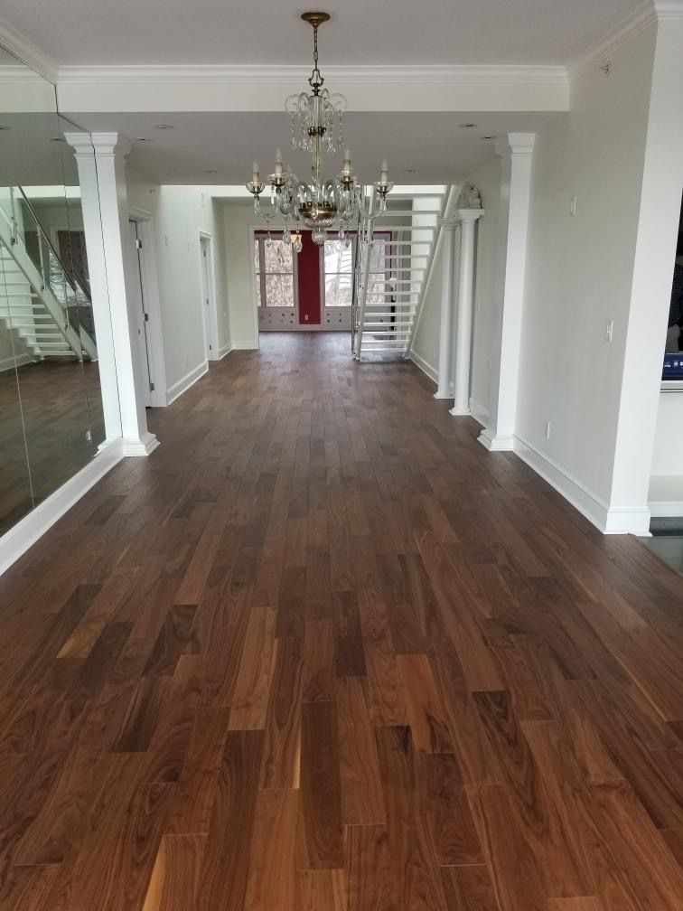 A large empty room with hardwood floors and a chandelier hanging from the ceiling.