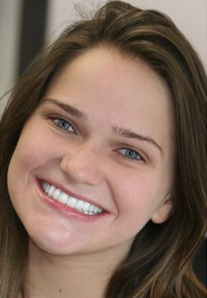 Woman smiling, showing white teeth, brown hair, looking at the viewer.